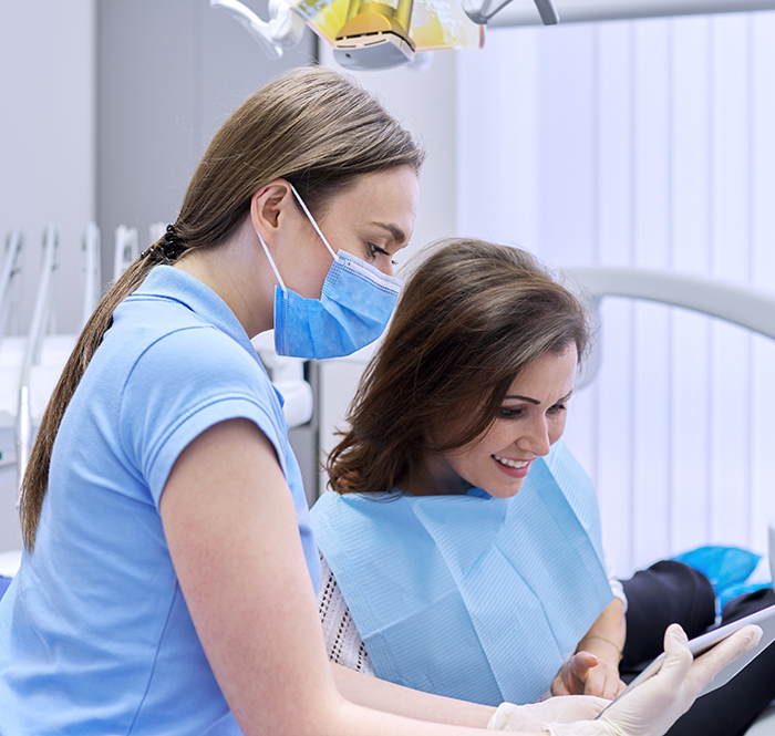 Dentist in mask showing dental patient a mirror