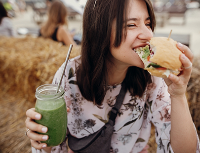 Woman biting a sandwich while holding a soda