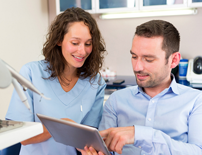 Female dentist showing male patient something on a tablet