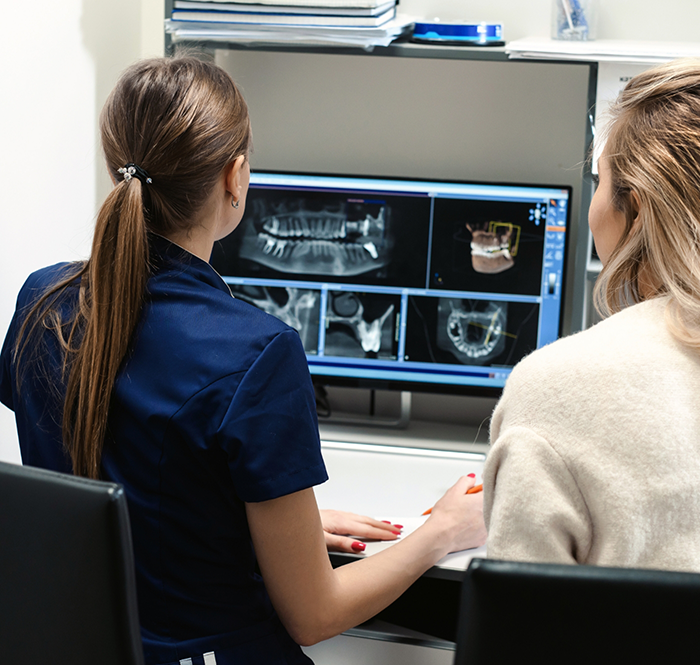 Dentist looking at dental X rays on computer monitor