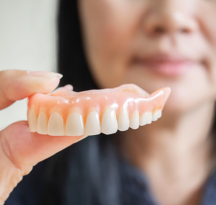 Close up of hand holding a full denture in Flower Mound