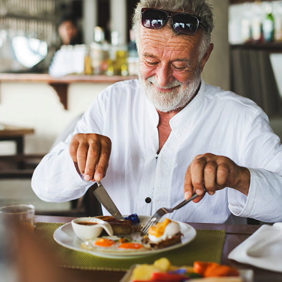 Senior man eating a meal with a knife and fork