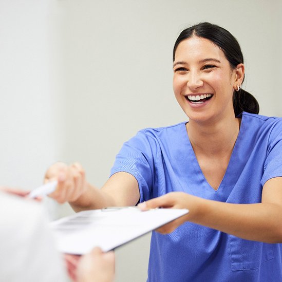 Dental assistant smiling while handing patient form