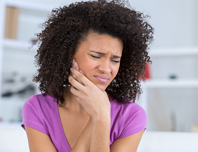 Woman in purple shirt rubbing jaw in pain