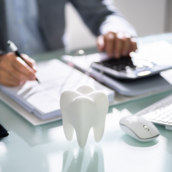 Tooth on desk with person using calculator in background