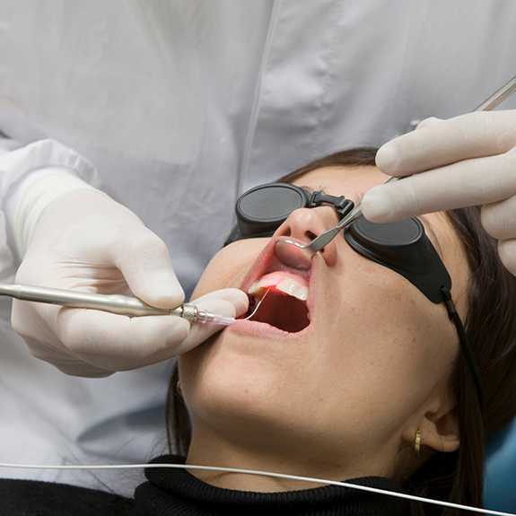 Patient with protective glasses receiving laser periodontal treatment