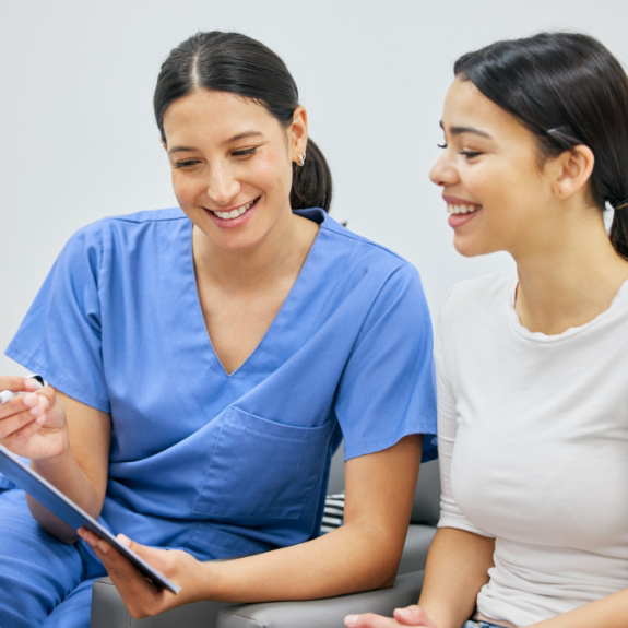 Dentist in blue shirt showing patient something on a clipboard