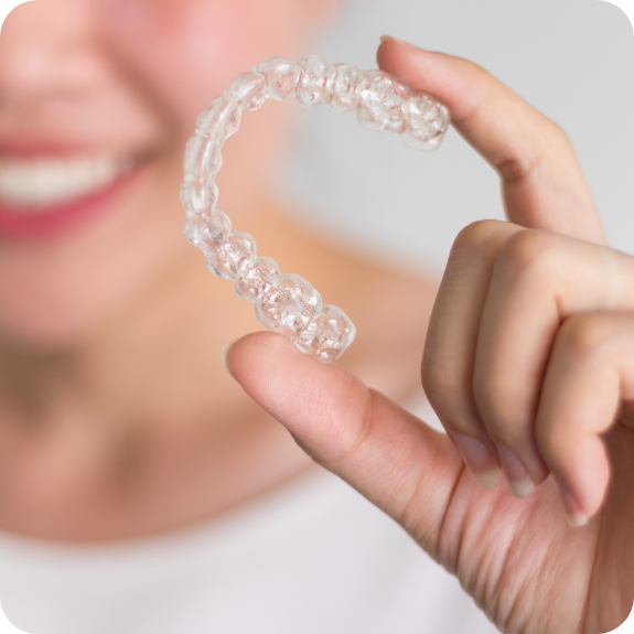 Close up of hand holding a clear aligner