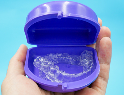 Hand holding case containing clear aligners