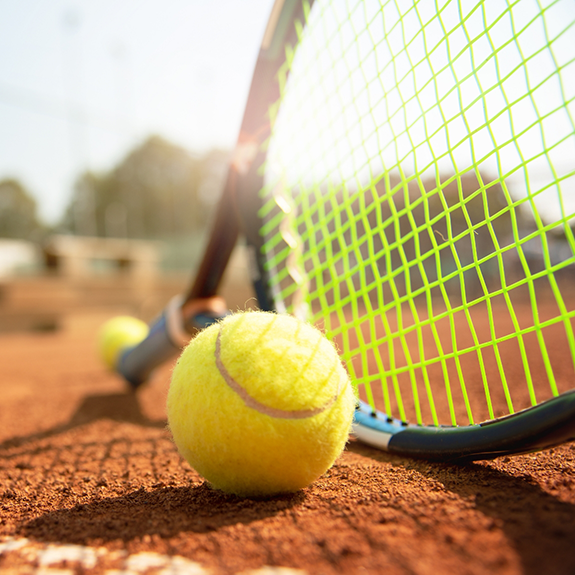 Tennis ball and racket lying on court