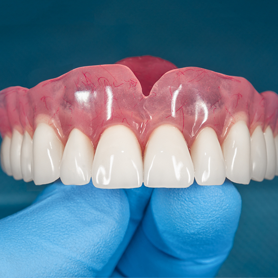 Close up of gloved hand holding a full denture