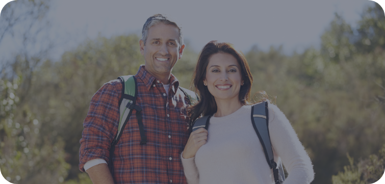 Man and woman with backpacks standing outside smiling