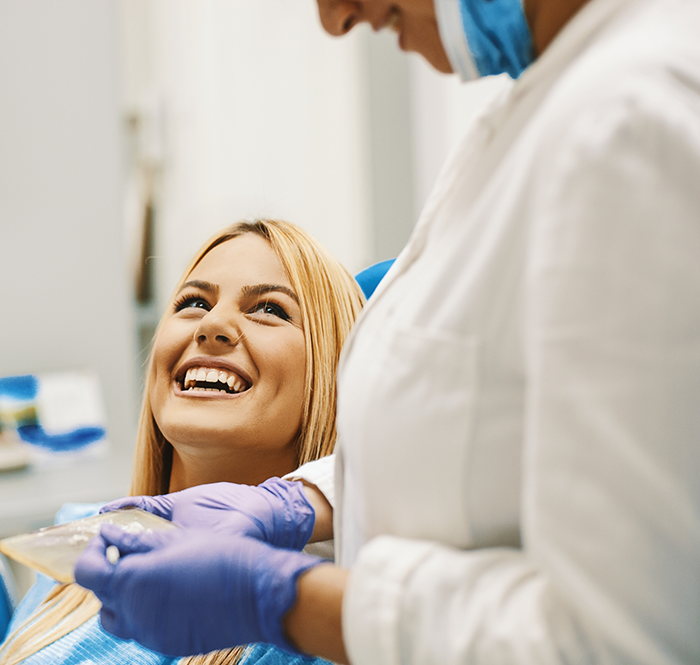 Blonde dental patient looking up at dentist and smiling