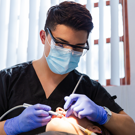 Dentist with mask performing oral cancer screening