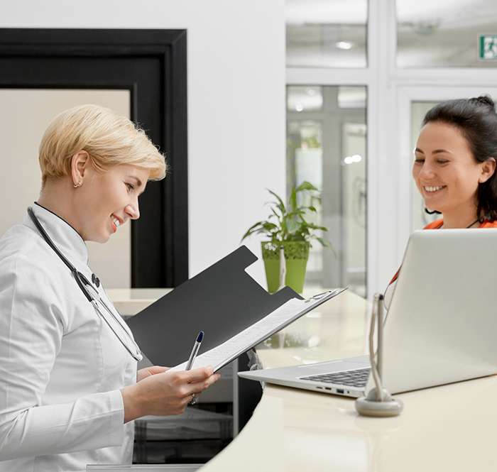 Dental team member at front desk looking through binder