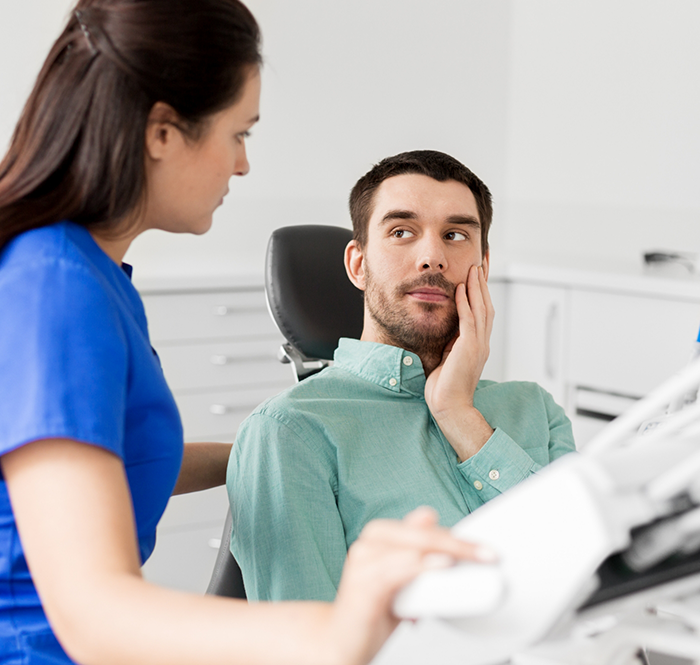 Male dental patient with tooth pain looking up at dentist