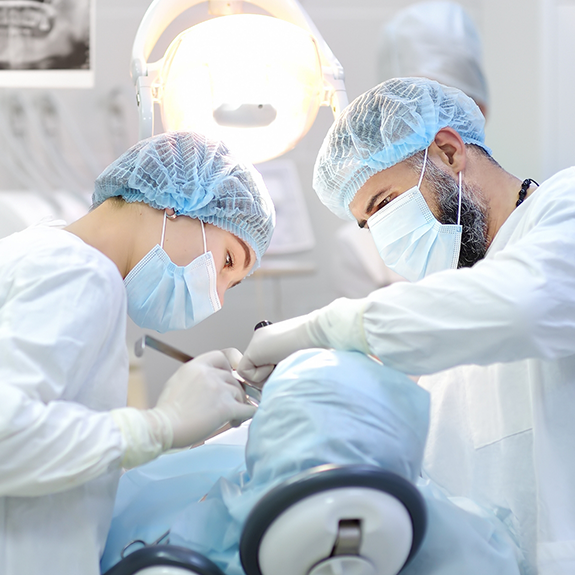 Dentist and team member wearing masks and performing a tooth extraction