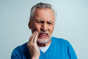 Man rubbing his chipped tooth